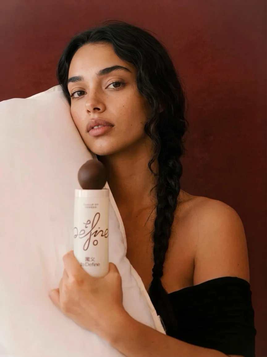 A person holds a clearly visible Define skincare bottle close to the camera.